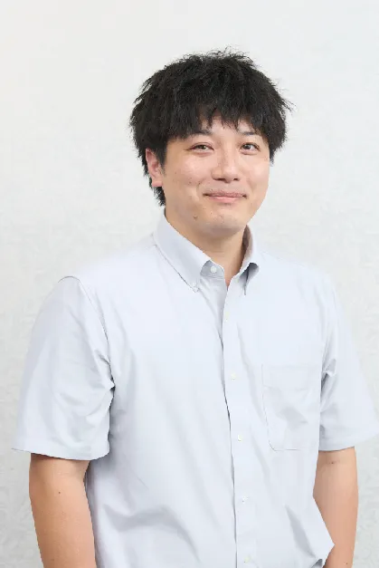 スーツを着た男性スタッフが笑顔で立っている写真